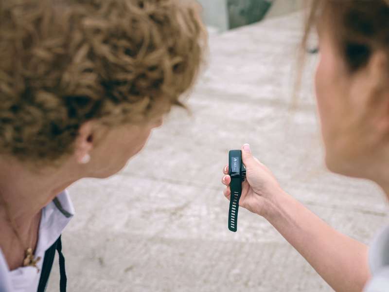 a woman shows an elderly woman a worn digital device