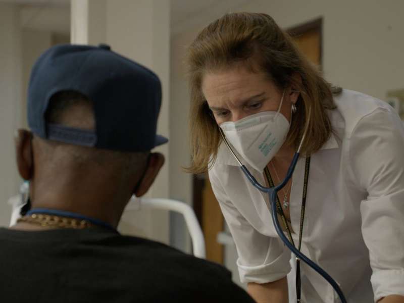 a health care worker with a stethoscope takes a patient's pulse