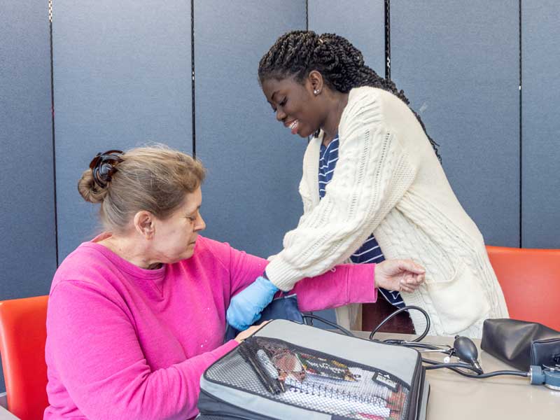 a health care worker in a community clinic takes someone's blood pressure