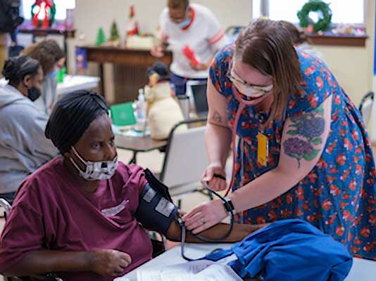 a health care worker takes a patient's blood pressure in a community clinic