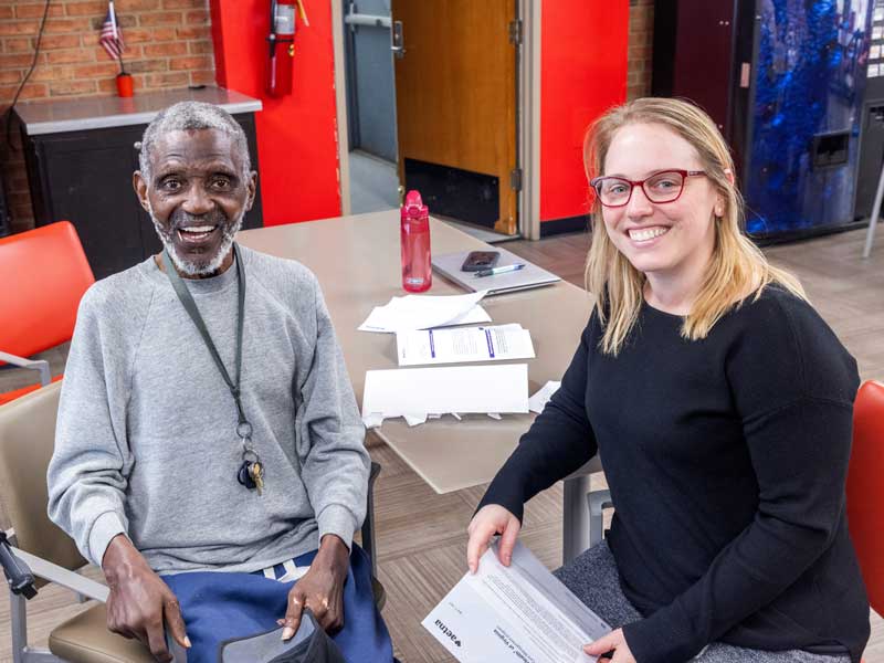 two people sitting at a table in a community health clinic smiling