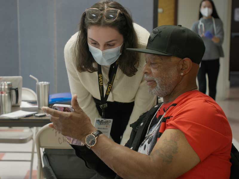 a patient and a health care worker in a clinic look together at a mobile phone the patient is holding