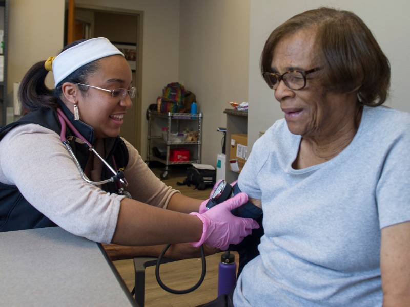 Kathie Falls, MSN, director of clinical operations of the Richmond Health and Wellness Program, takes the blood pressure of program participant James Peace.