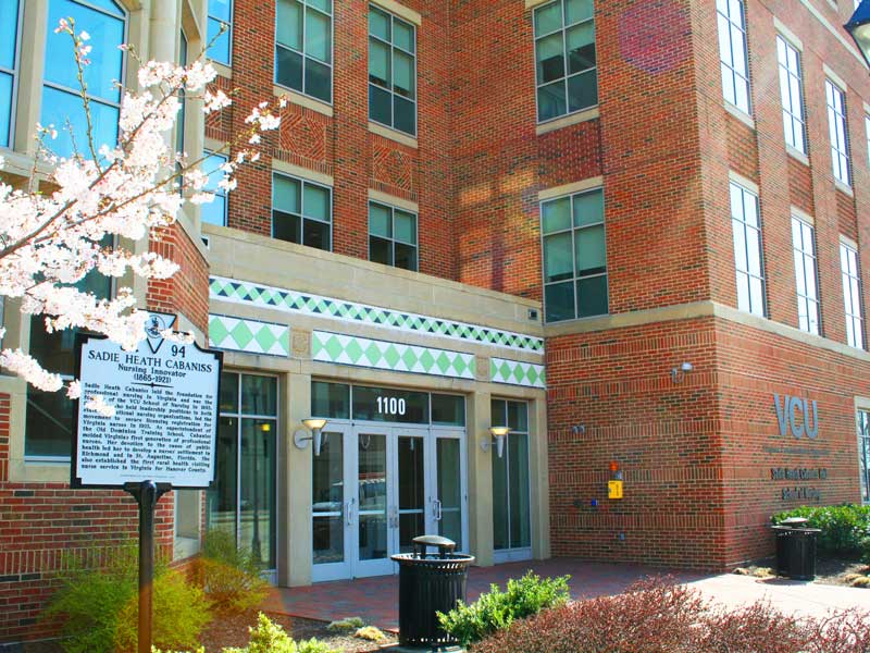 the front door of cabaniss hall at v.c.u. with a historical marker and tree in bloom